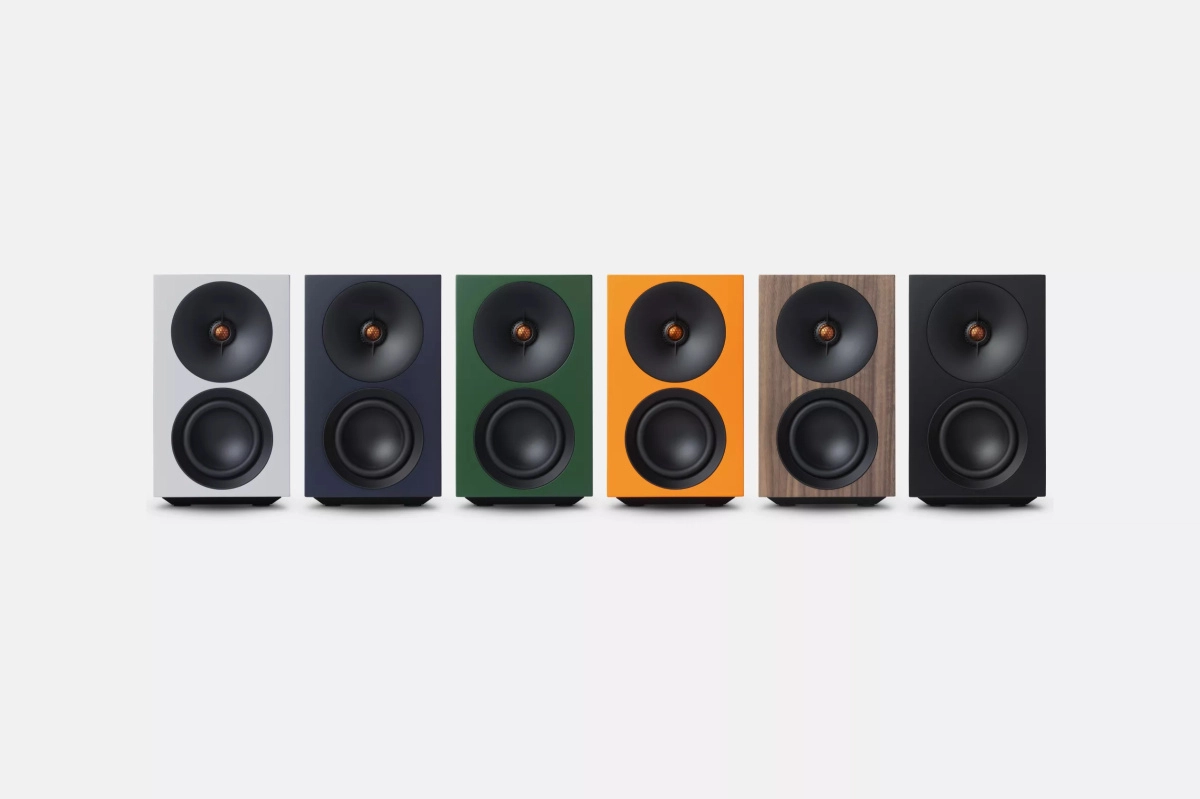 Šest barevných provedení Cambridge Audio L/R S v řadě — bílé, tmavě modré, zelené, oranžové, ořechové a černé — na světle šedém pozadí