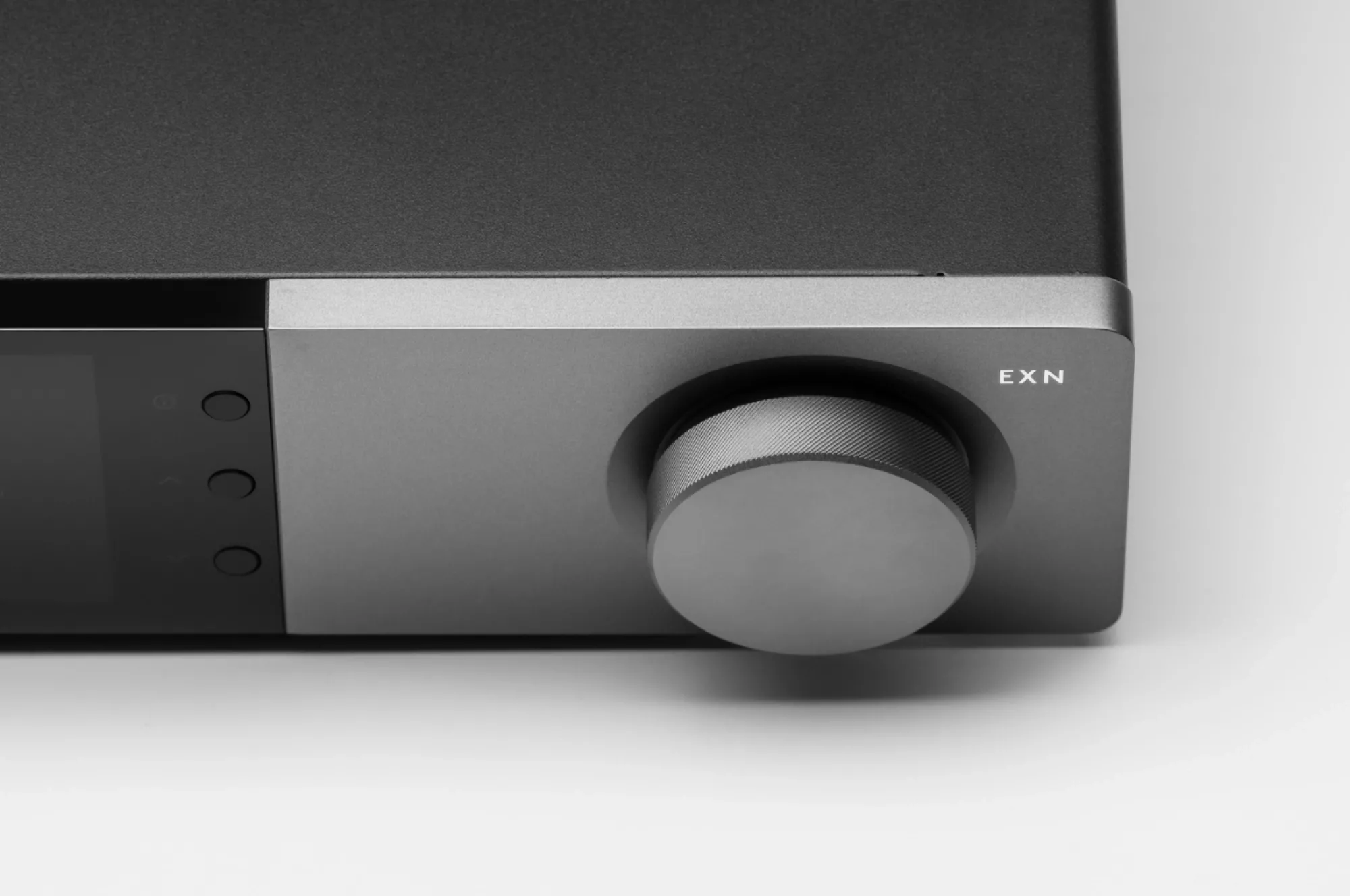 Cambridge Audio EXN100 a zesilovač řady EX v obývacím pokoji pod nástěnnou televizí, vedle sloupová reprosoustava u cihlové stěny