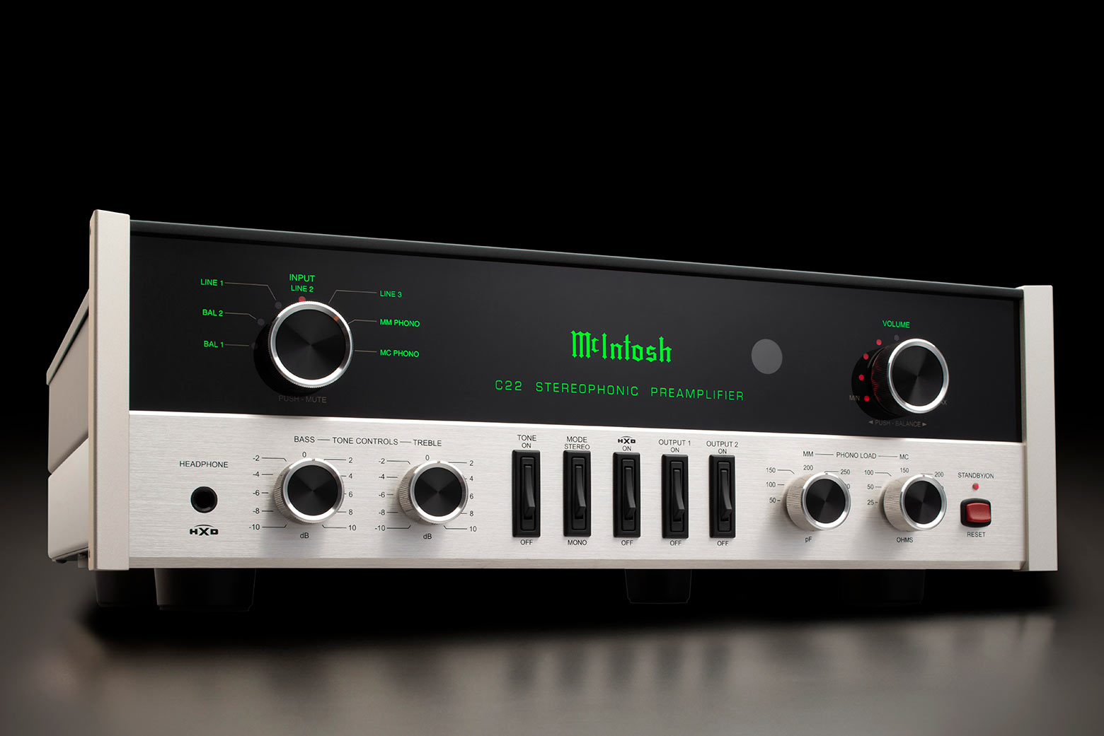 McIntosh C22 Mk V z úhlu — retro přední panel z černého skla a kartáčovaného hliníku se zeleným podsvícením, knoflíky tónových korekcí a phono load na tmavém pozadí