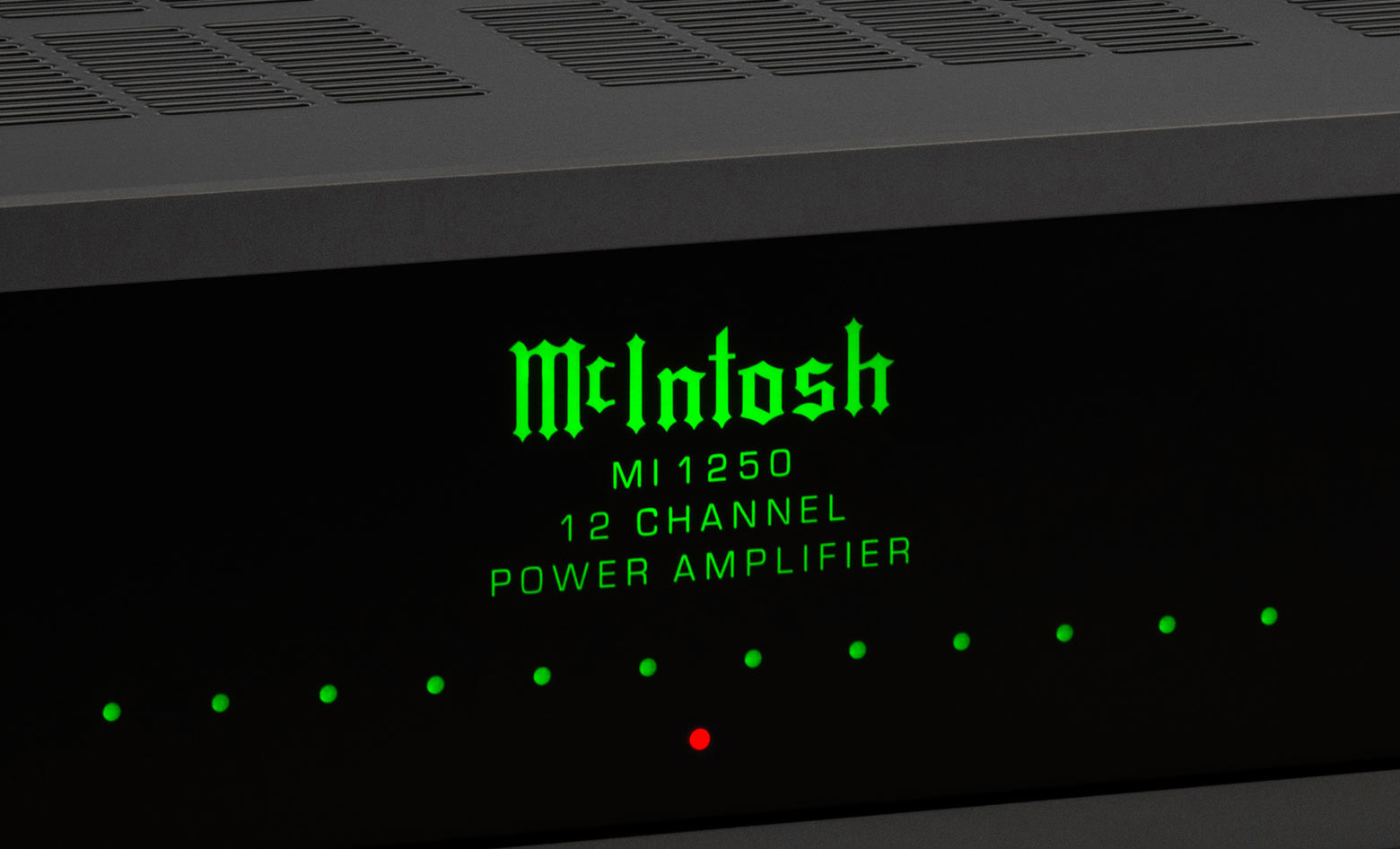 Detail černého skleněného čelního panelu MI1250 s podsvíceným zeleným logem McIntosh a indikátory kanálů