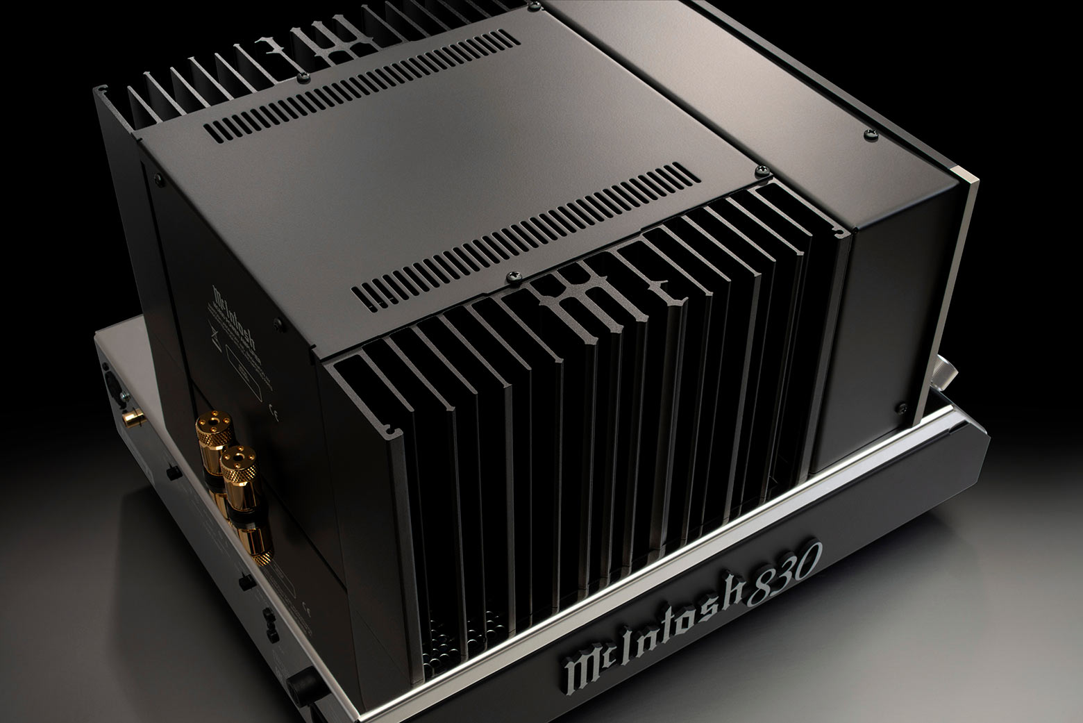 Horní pohled na McIntosh MC830 s odhalenými černými monogramovanými chladiči a otevřeným průmyslovým šasi