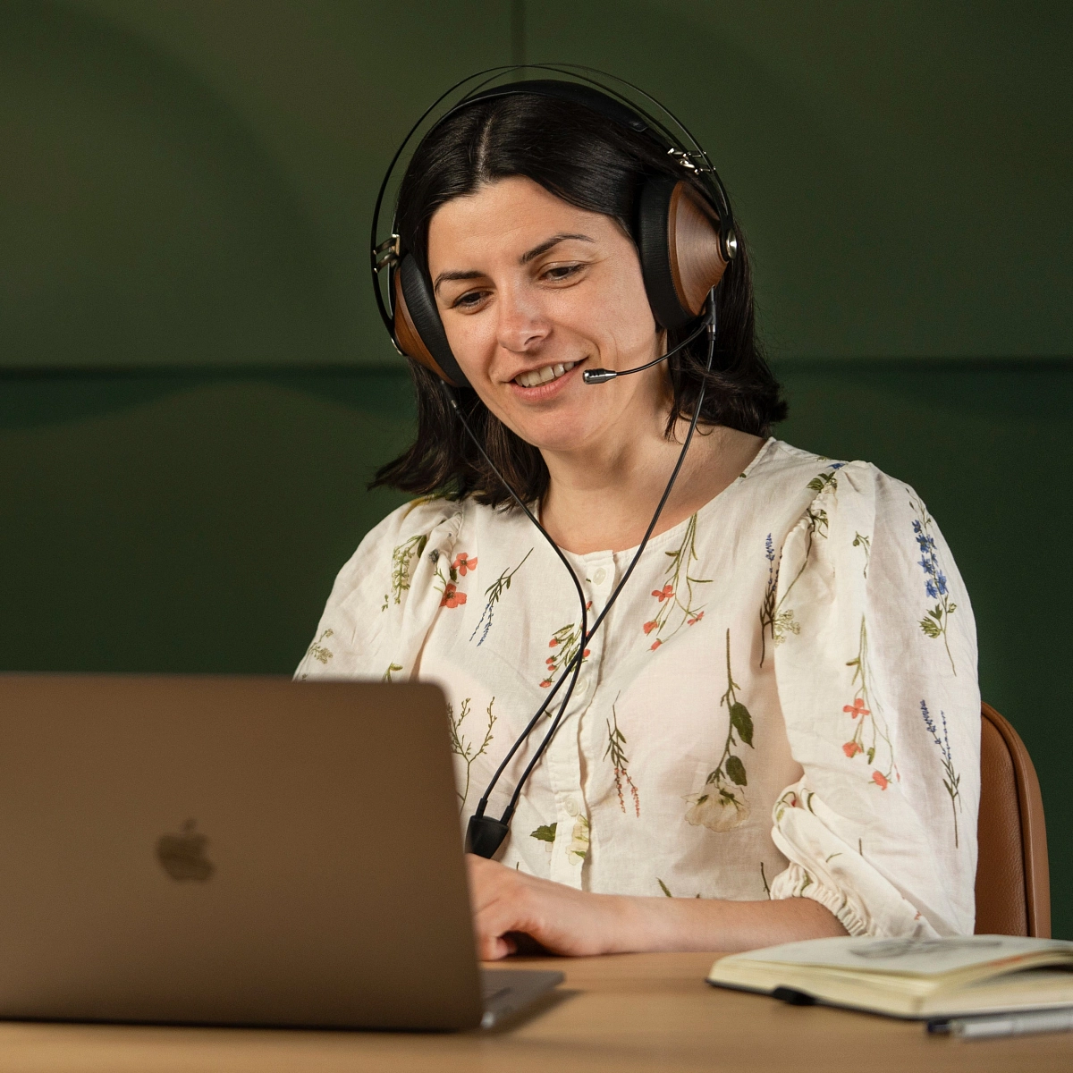 Žena se sluchátky Meze Audio a mikrofonem Boom Mic na videohovoru u notebooku