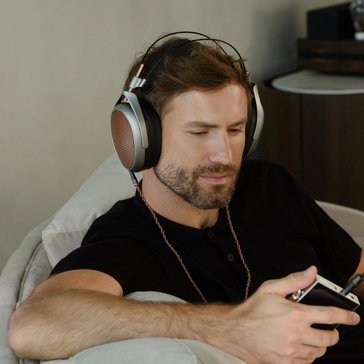 Muž s nasazenými otevřenými sluchátky Meze Audio Poet při uvolněném domácím poslechu