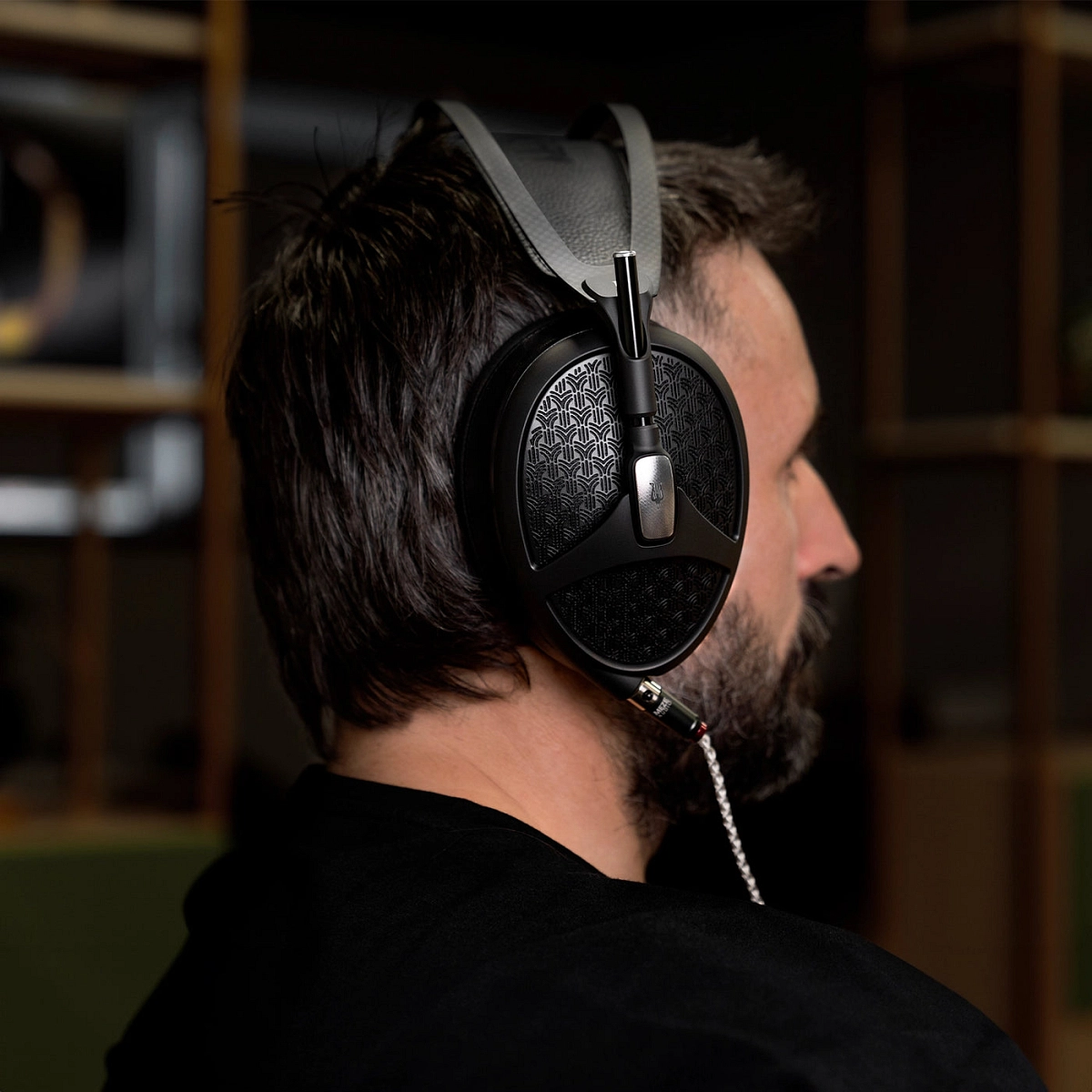 Muž s nasazenými sluchátky Meze Audio Empyrean II z profilu při domácím poslechu