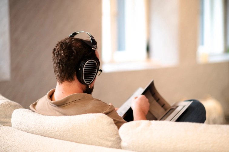 Pohled zezadu na otevřená sluchátka HIFIMAN Ananda s charakteristickou mřížkou měniče během poslechu na pohovce