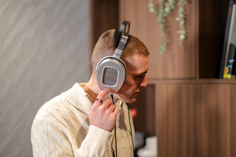Detail nasazených sluchátek HIFIMAN HE1000 Unveiled, otevřená mušle s mřížkovaným krytem planárně-magnetické membrány