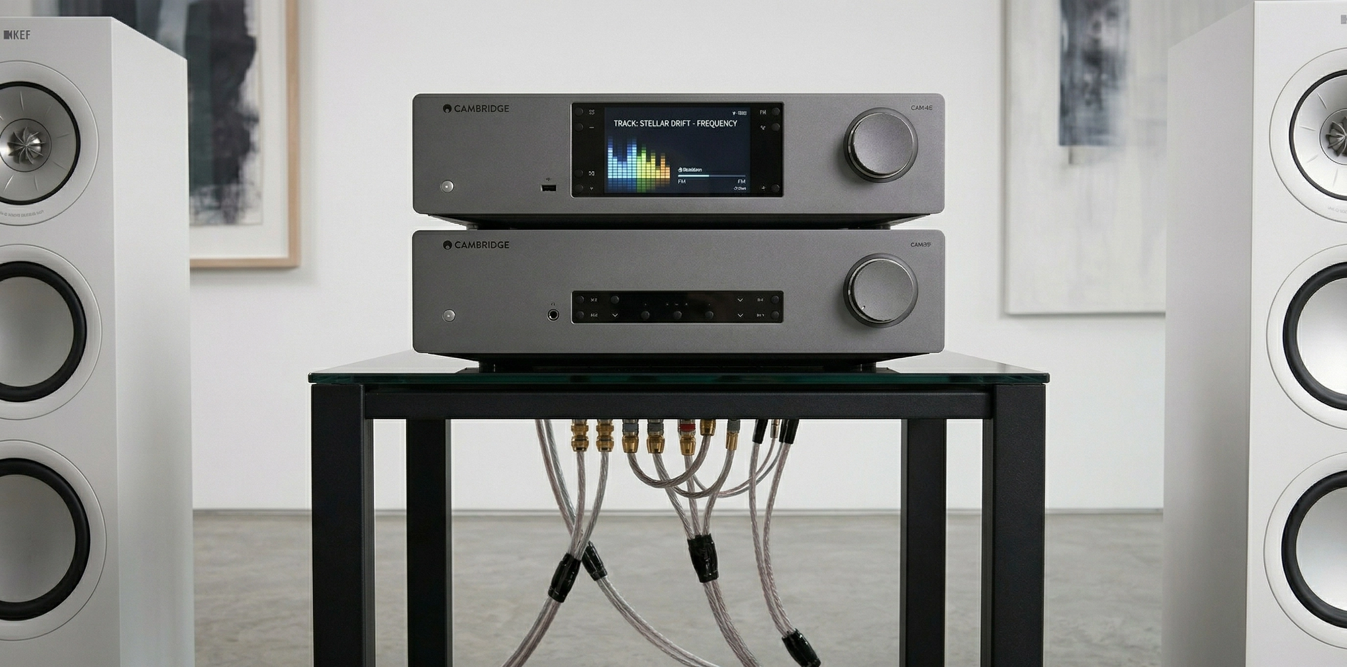 Detail elektroniky Cambridge Audio CXN 100 a CXA81 Mk II na skleněném stolku s propojovací kabeláží Nordost Red Dawn 3 a reproduktory KEF po stranách