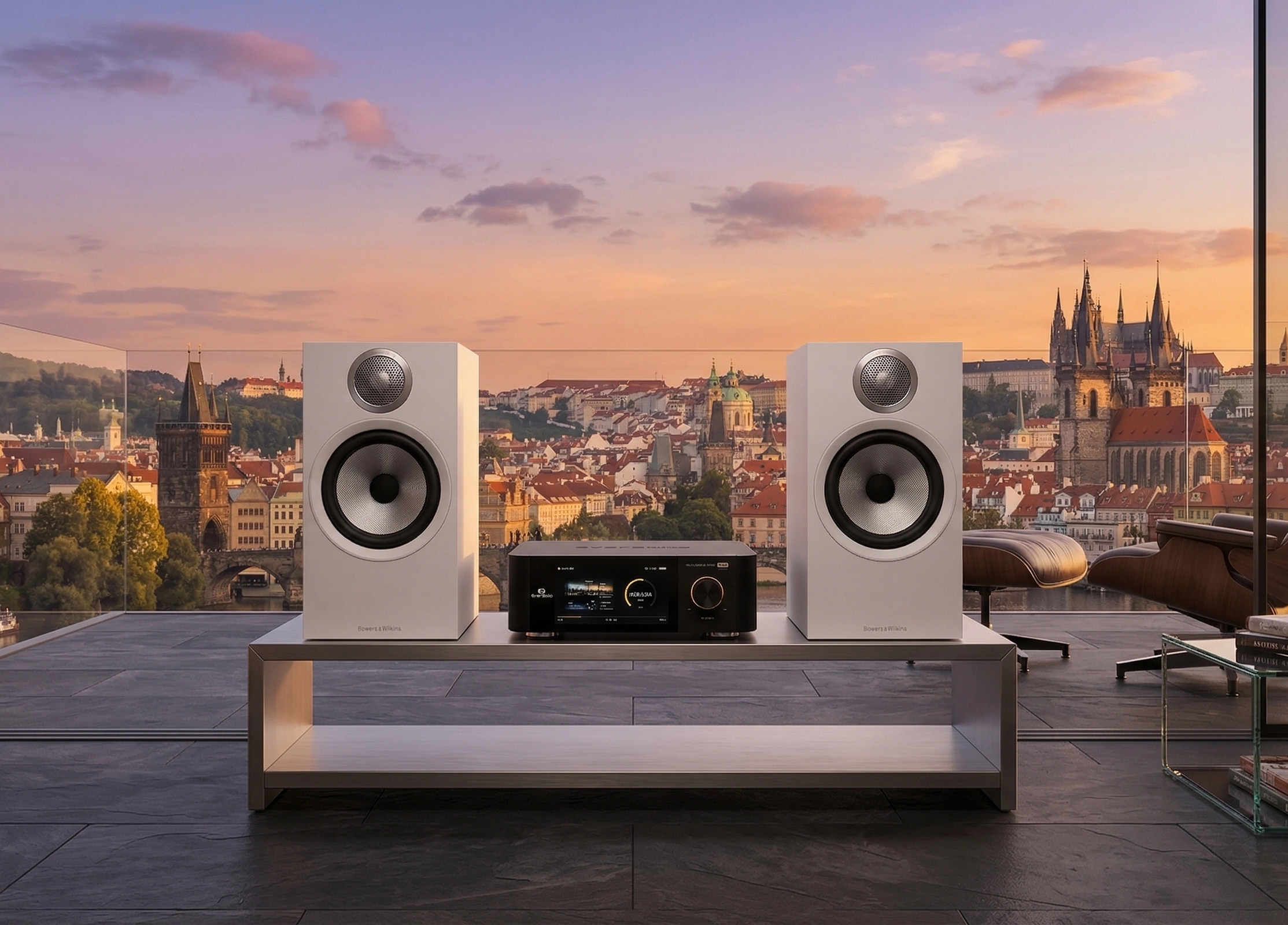 Detail bílých reproduktorů Bowers & Wilkins 606 S3 s jednotkou EverSolo mezi nimi, v pozadí panorama Prahy při západu slunce