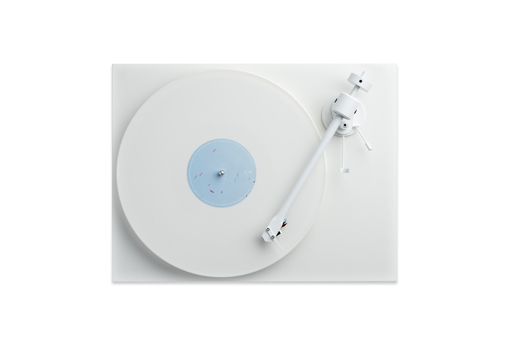 Pohled shora na Pro-Ject T1 White Edition s bílou vinylovou deskou se světle modrým labelem, bílým rovným ramenem, protizávažím a páčkou zdvihu ramene