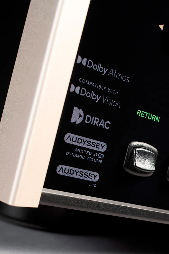 Detail levého okraje čelního panelu McIntosh MX124 s logy Dolby Atmos, Dolby Vision, Dirac a Audyssey MultEQ XT32