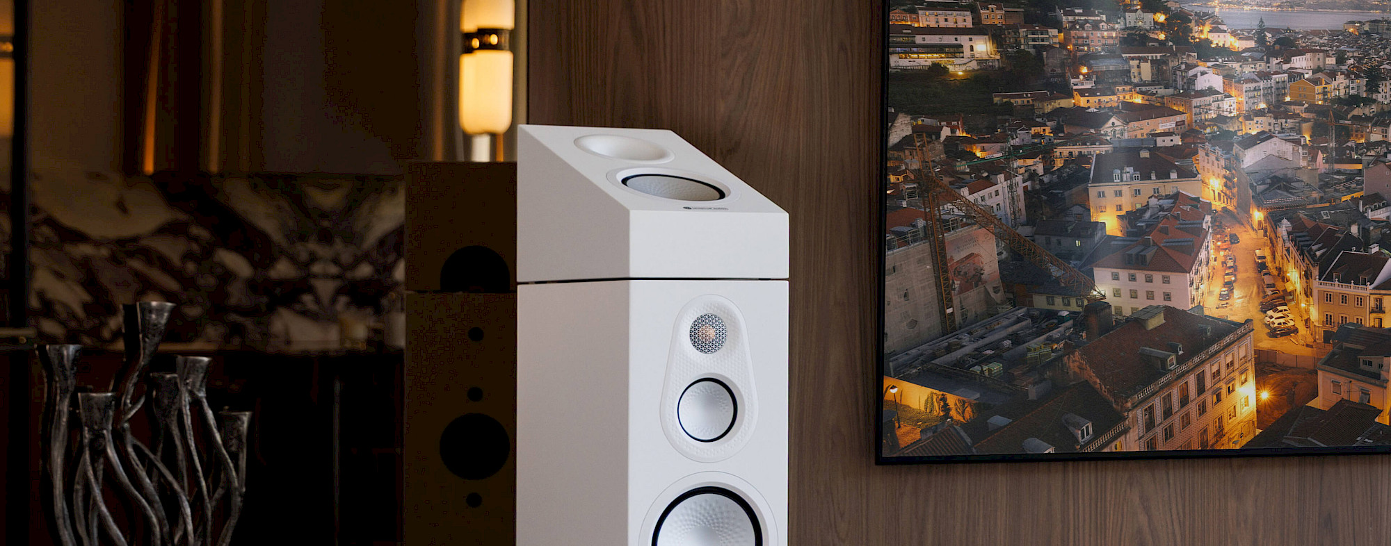 Modul Monitor Audio Silver AMS 8G v provedení Satin White nasazený na horní ploše sloupového reproduktoru vedle televize