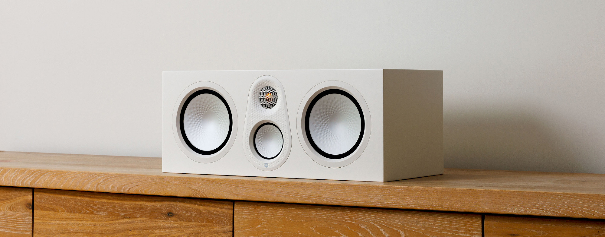 Monitor Audio Silver Centre 8G v provedení Satin White na dubovém sideboardu
