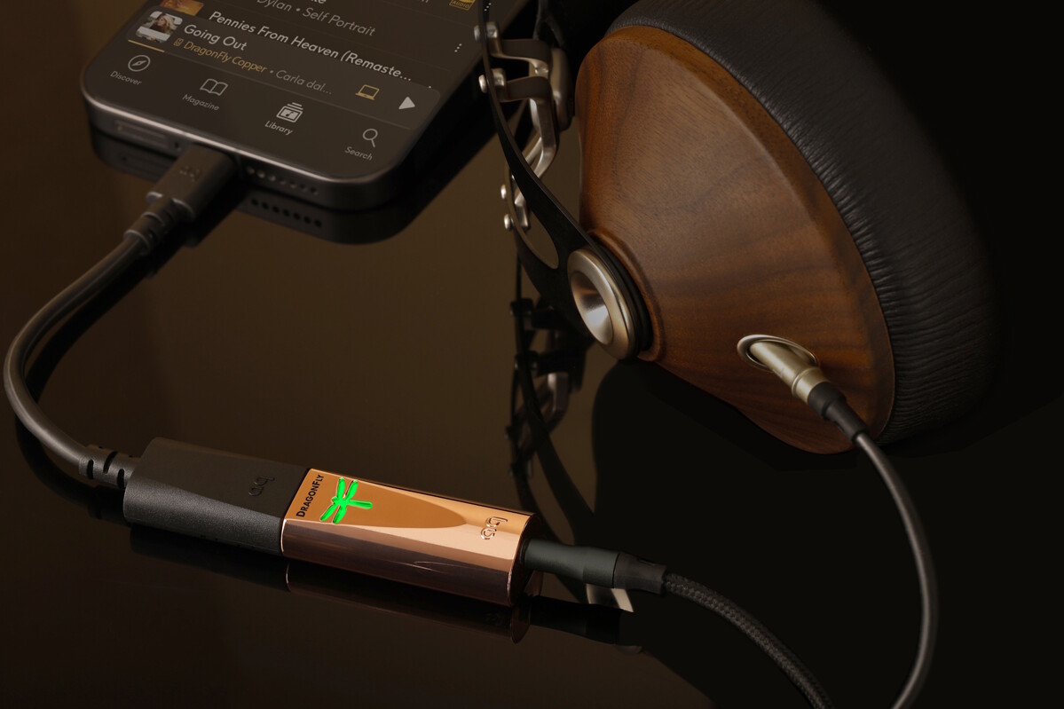 AudioQuest DragonFly Copper se zeleně svítící vážkou, propojený s telefonem a s dřevěnými planárními sluchátky