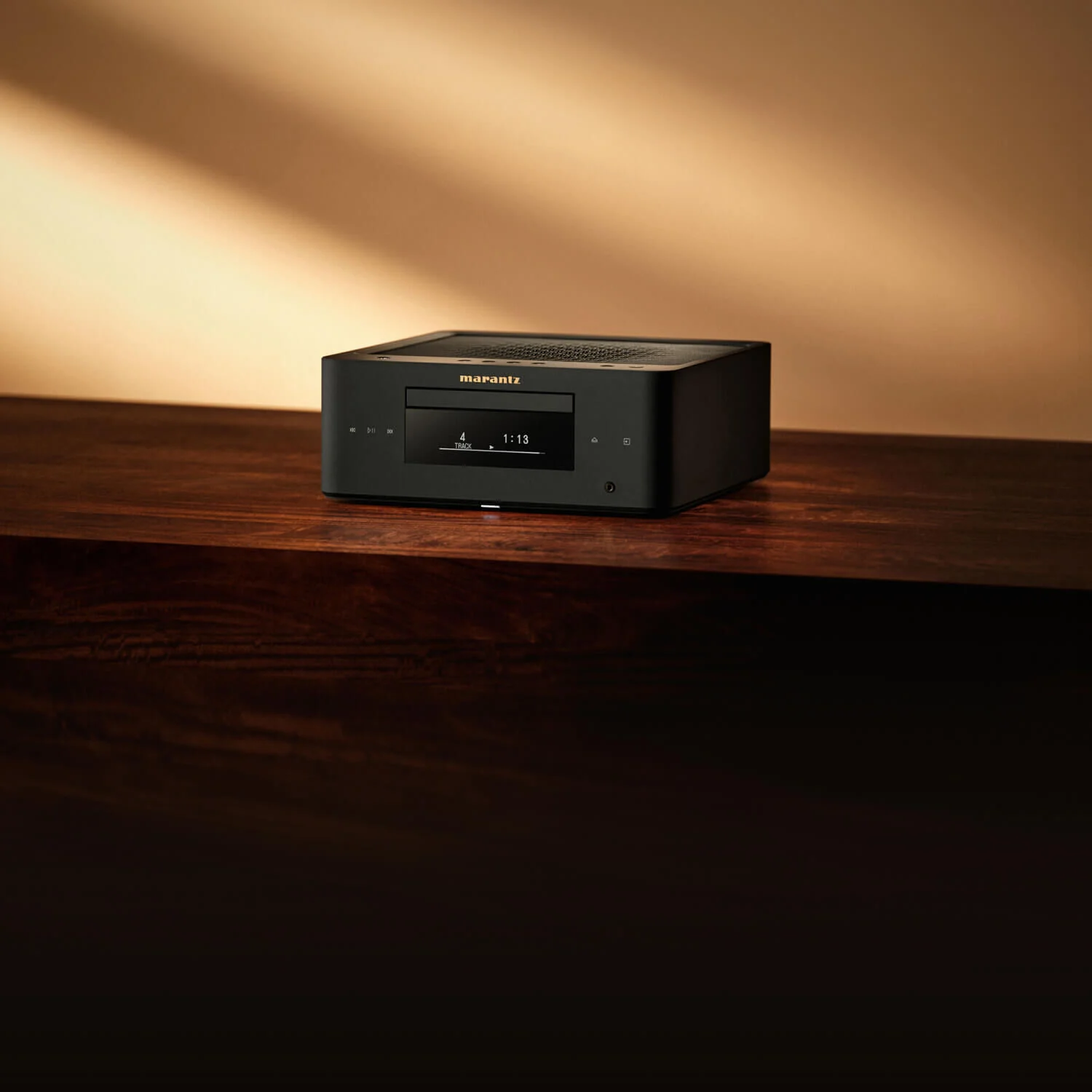 Marantz MCR 60n DAB v černém provedení na masivní dřevěné komodě před stěnou s teplým večerním světlem