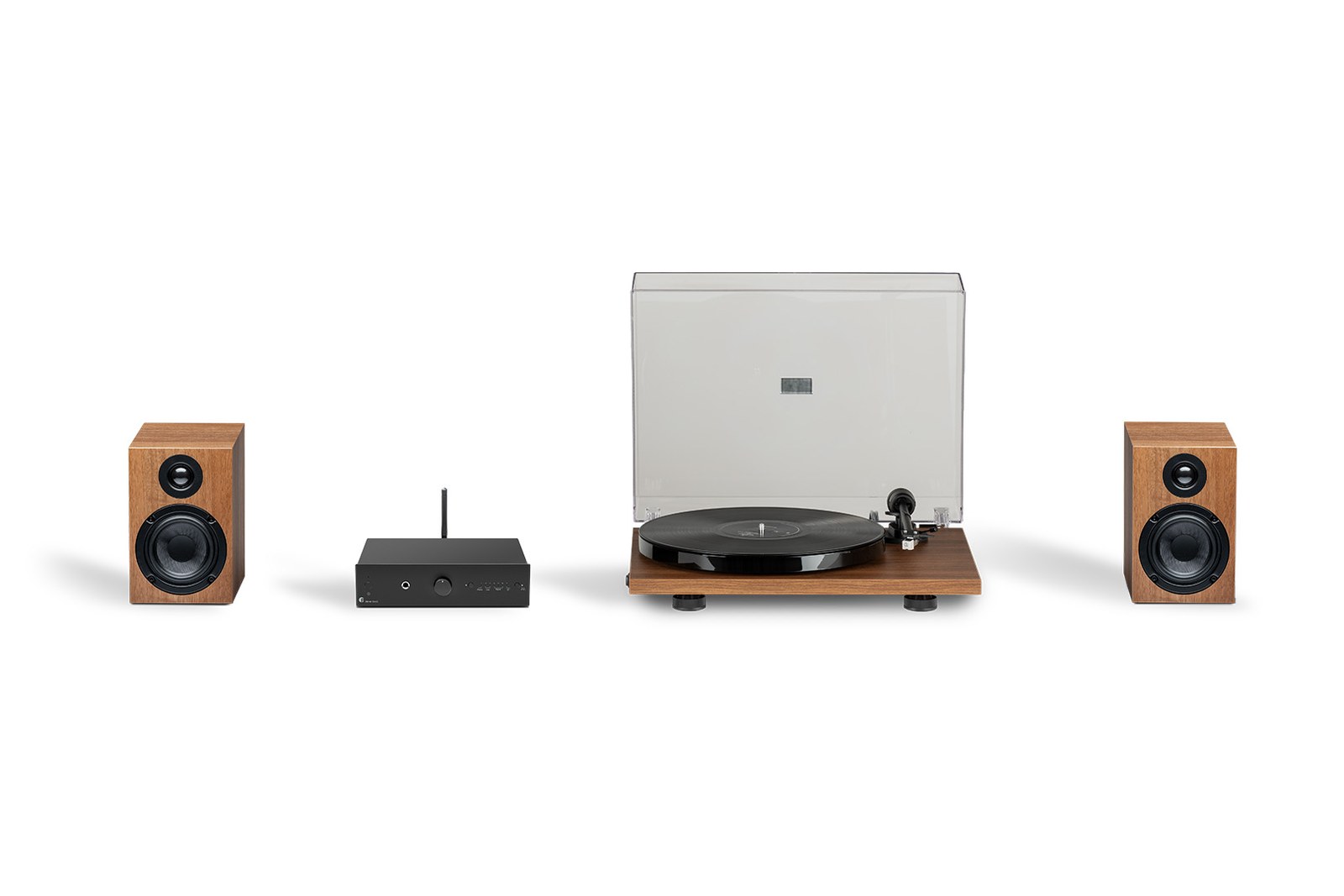 Sestava Pro-Ject Stereo Set E Phono v ořechovém provedení na bílém pozadí: reprosoustavy po stranách, černý zesilovač a gramofon s ořechovou deskou a zvednutým krytem