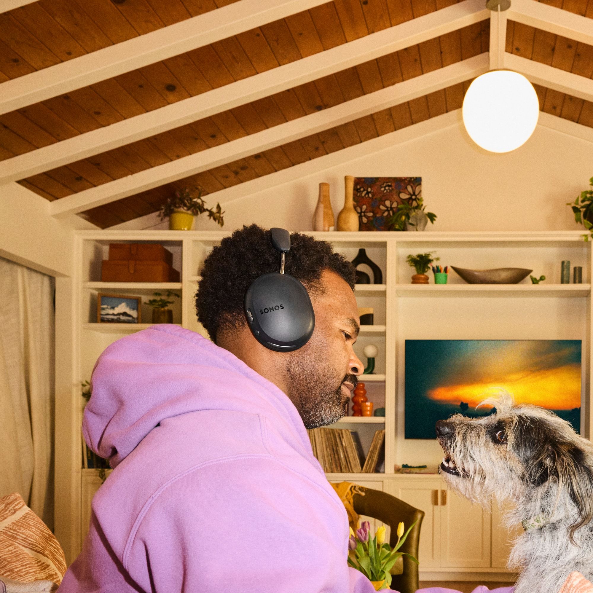 Sestava: soundbar Sonos Arc Ultra pod televizí v obývacím pokoji a sluchátka Sonos Ace Ultra položená vedle na stolku, formát 1:1