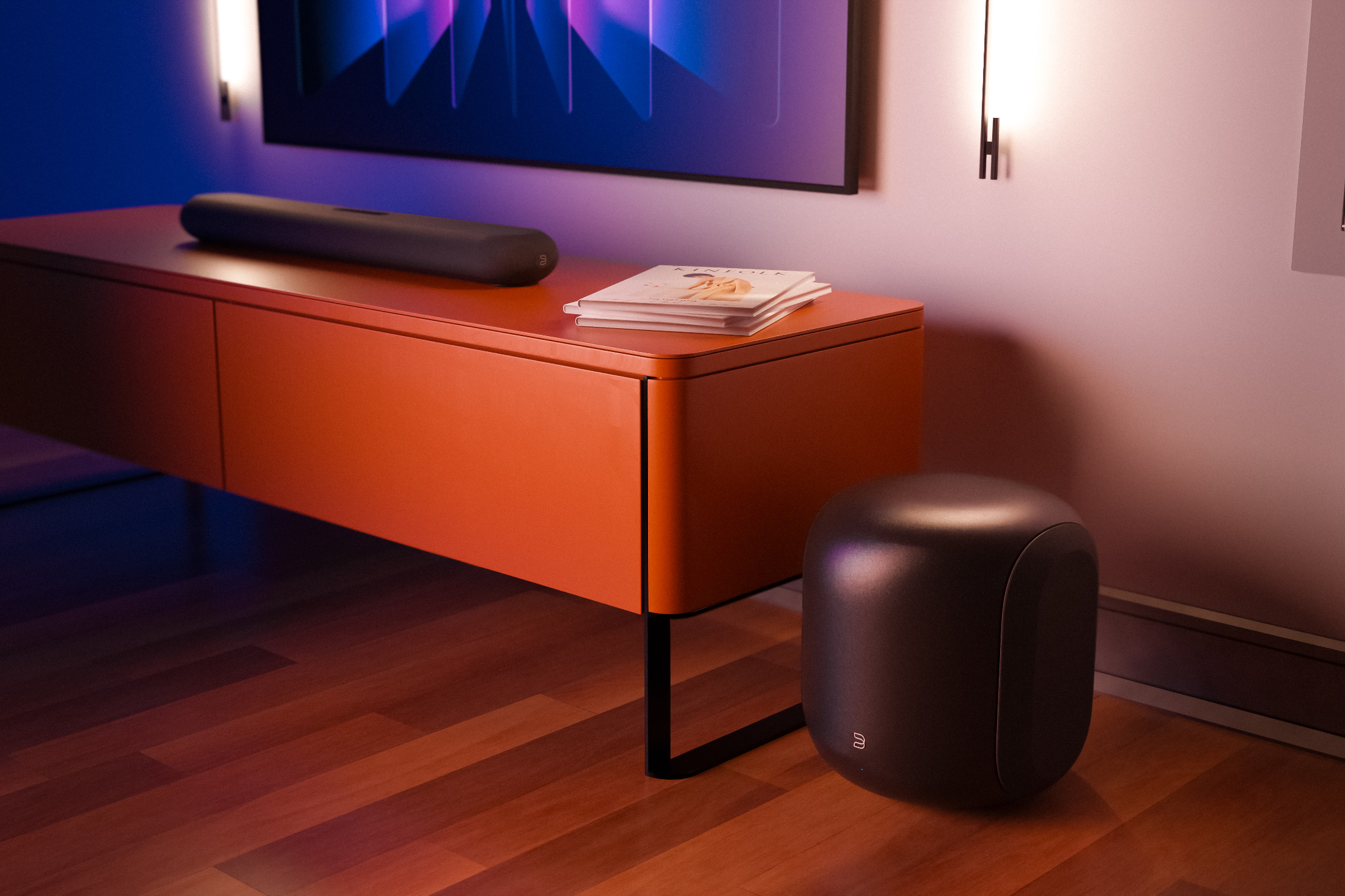 Večerní obývací pokoj s oranžovou komodou, televizí a soundbarem, subwoofer Bluesound PULSE SUB stojí na dřevěné podlaze