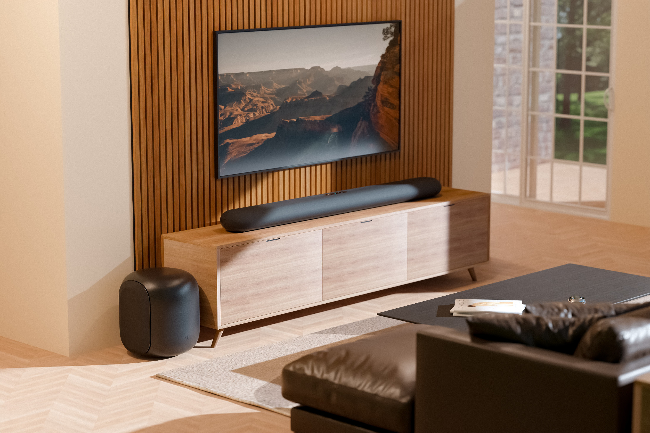 Bluesound PULSE SUB v černém provedení stojí na podlaze obývacího pokoje s dřevěnou lamelovou stěnou, televizí a soundbarem na komodě