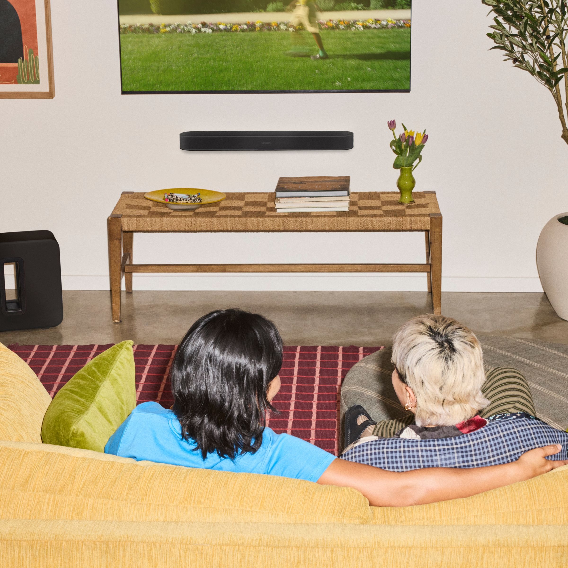 Sestava v obývacím pokoji: Sonos Beam Ultra pod televizí, Sonos Sub Mini u stěny a dva Sonos Era 100 za pohovkou