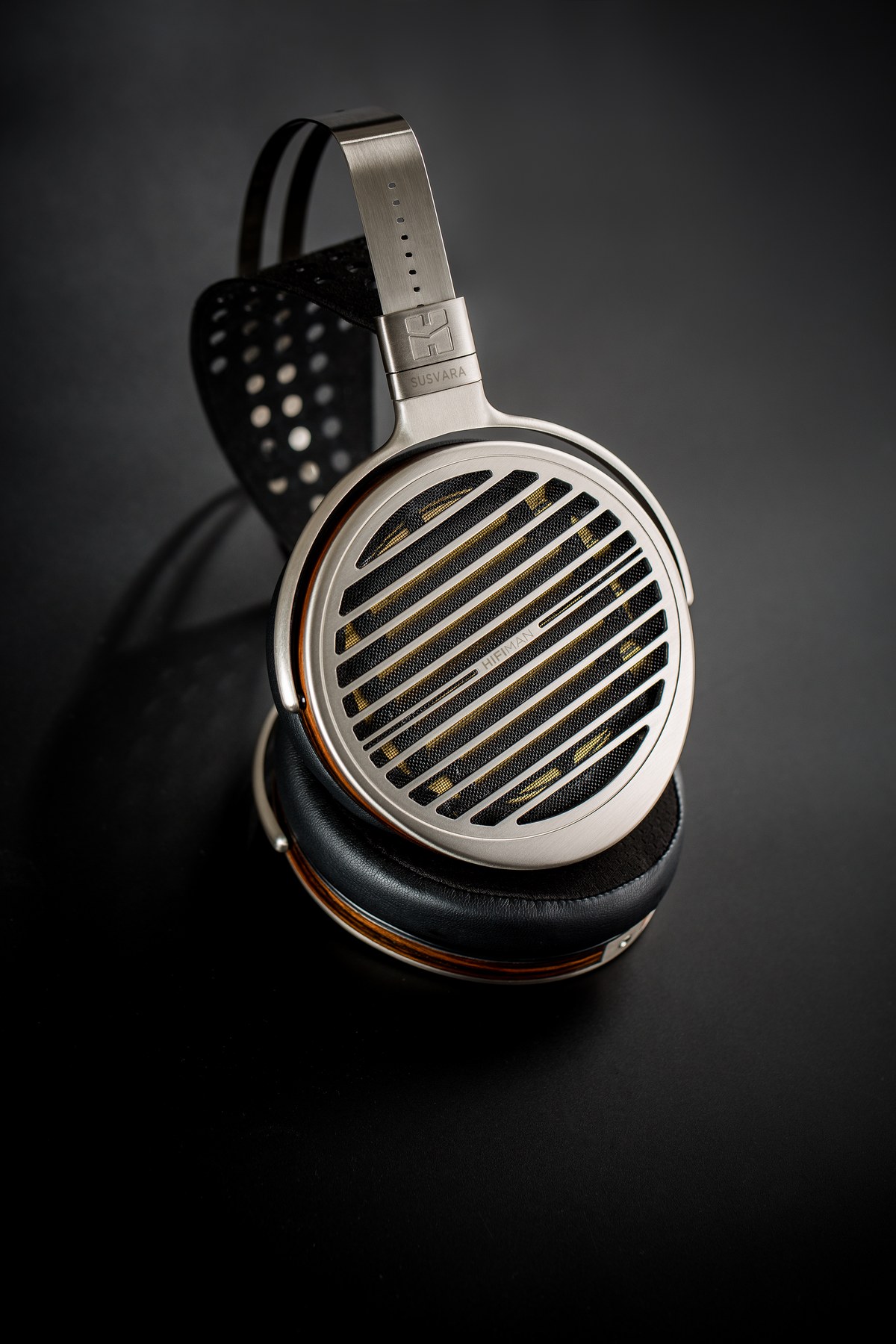 HIFIMAN Susvara v šikmém pohledu na tmavém pozadí — otevřená záda mušlí a dřevěný lem