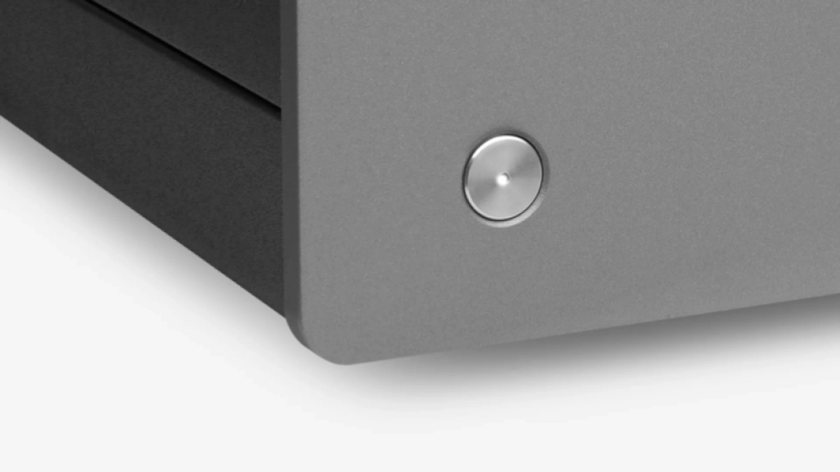 Detail rohu celokovového šasi Cambridge Audio MXW70 v barvě Lunar Grey s tlačítkem napájení