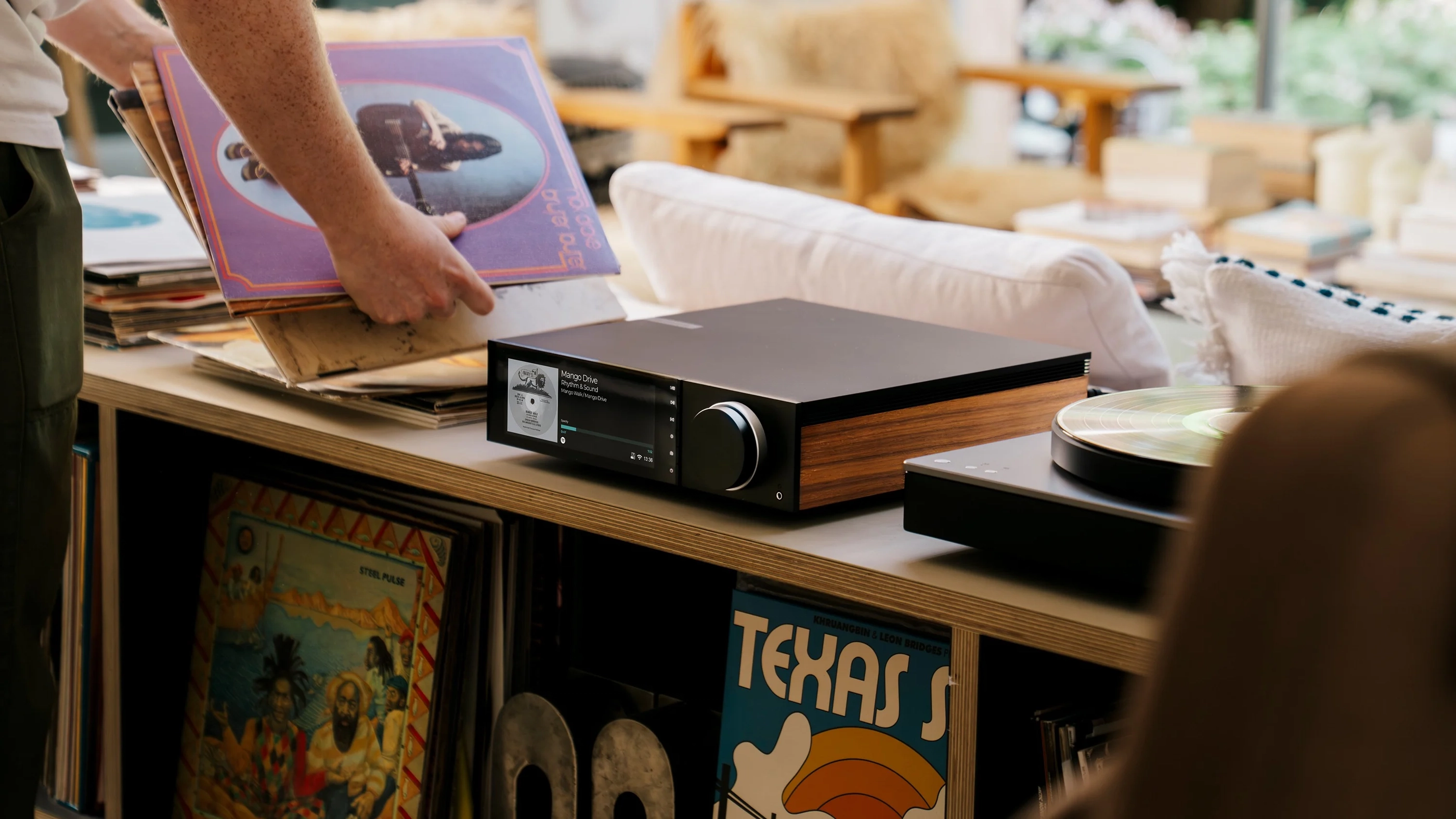Cambridge Audio EVO 150 SE na dřevěné komodě vedle sbírky gramofonových desek
