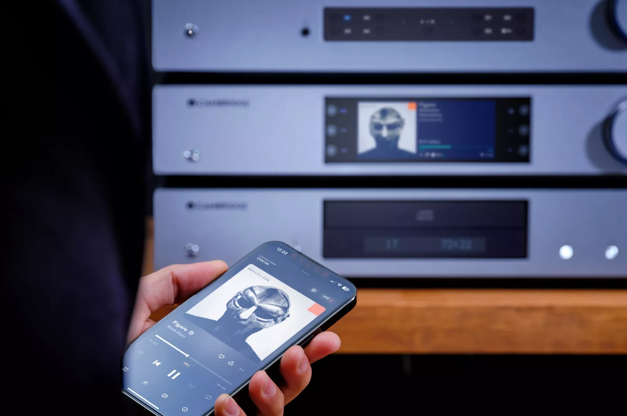 Telefon s hudební aplikací před stříbrnou sestavou Cambridge Audio s přehrávačem a zesilovačem