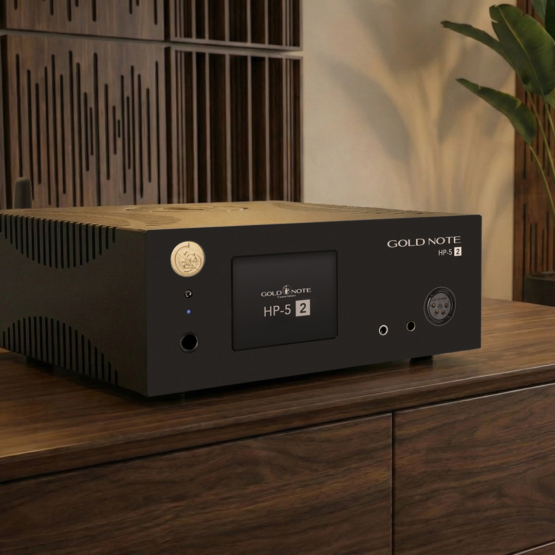 Detail čelního panelu Gold Note HP-5.2 s dotykovým displejem, zlatým otočným ovladačem a sluchátkovými konektory, na ořechové komodě