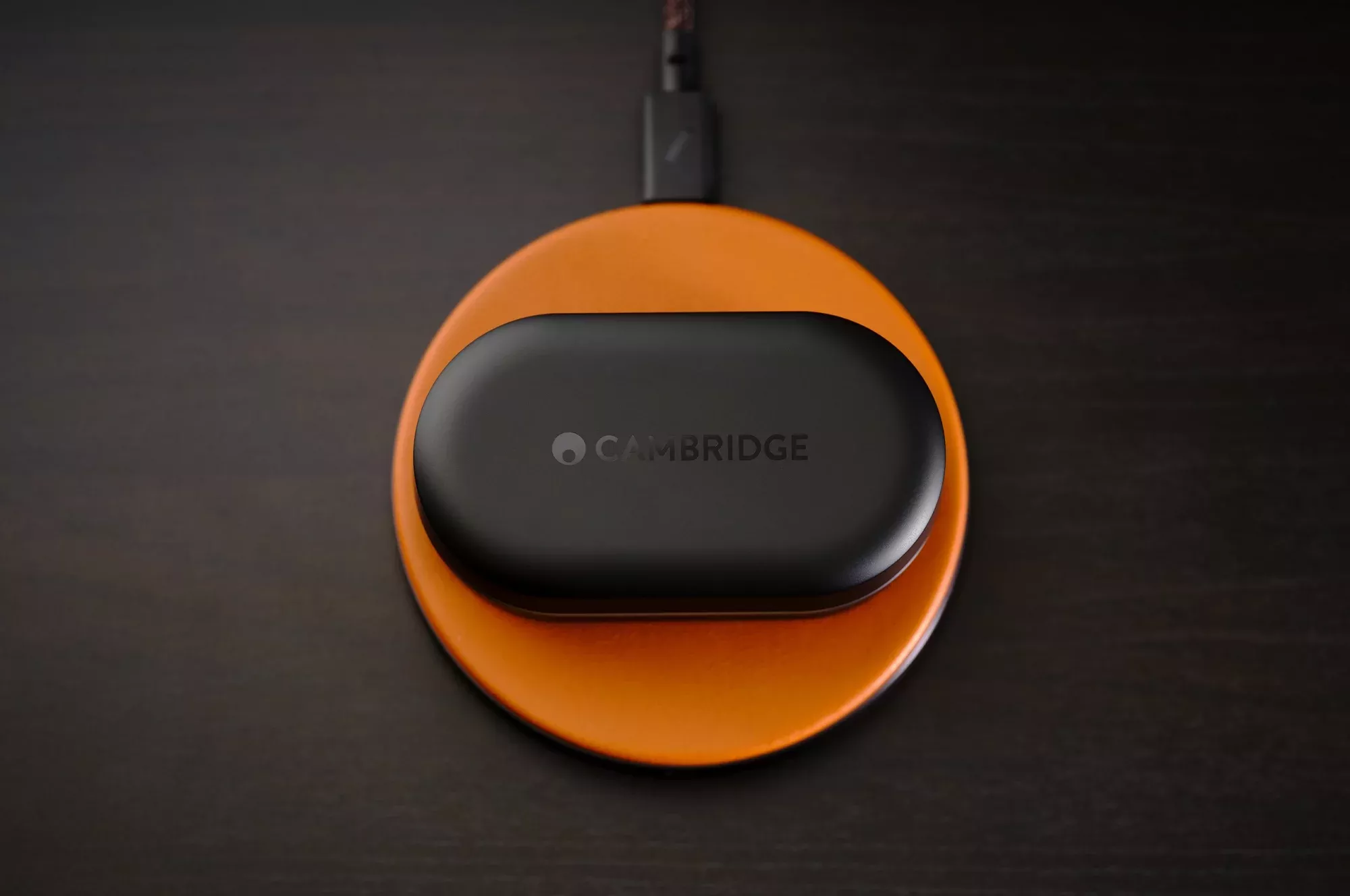 Nabíjecí pouzdro sluchátek Cambridge Audio Melomania M100 na bezdrátové nabíjecí podložce Qi