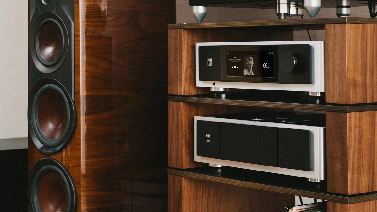 NAD M33 V2 a koncový zesilovač NAD M28 v dřevěném HiFi racku vedle leštěných ořechových sloupových reproduktorů