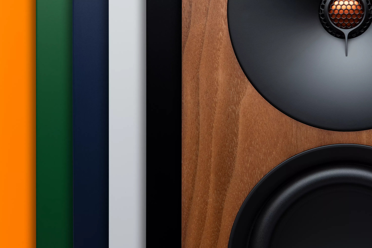 Šest barevných provedení Cambridge Audio L/R X jako svislé pruhy vedle detailu ořechové dýhy s výškovým a basovým měničem
