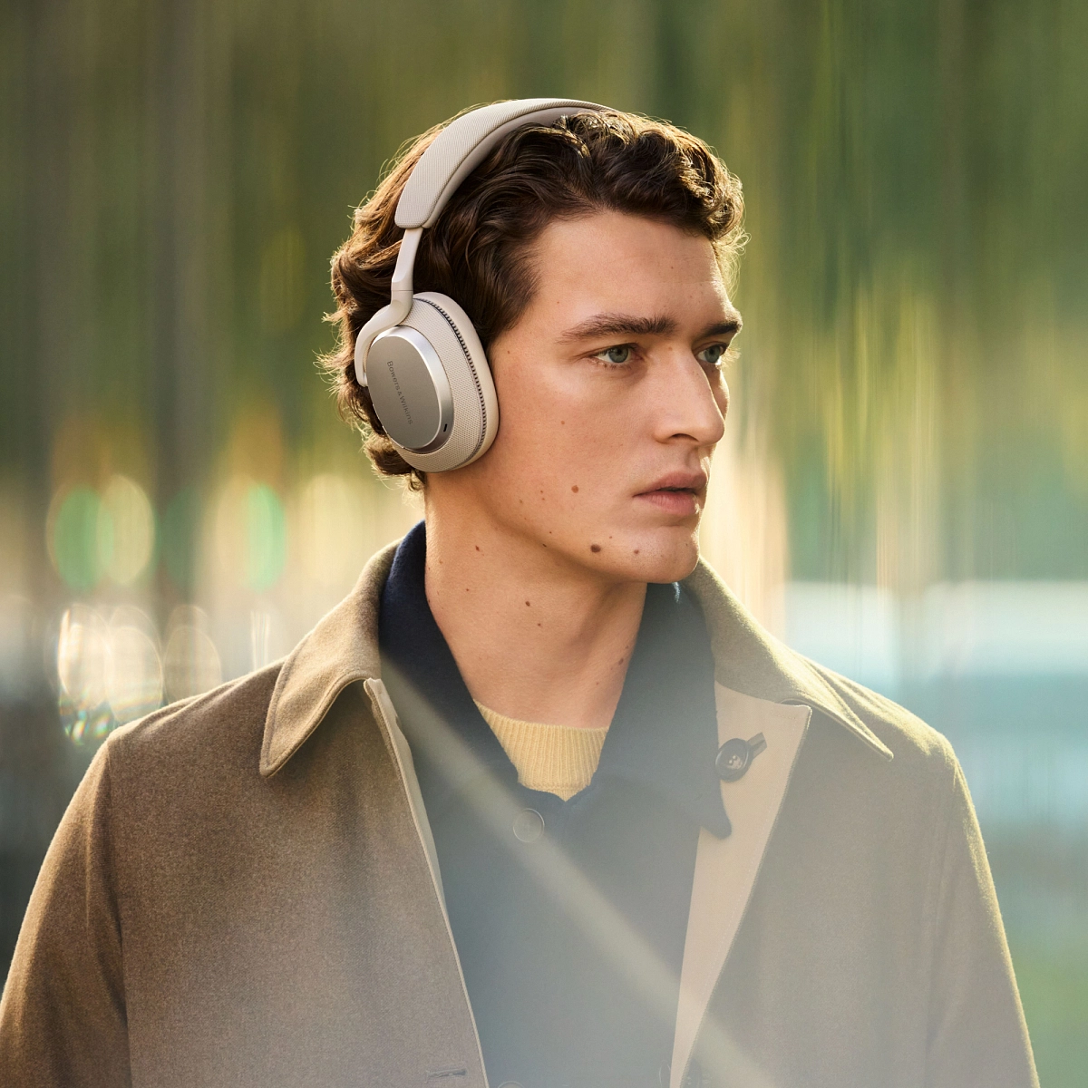Muž v kabátě venku se sluchátky Bowers & Wilkins Px7 S3 ve stříbrném provedení