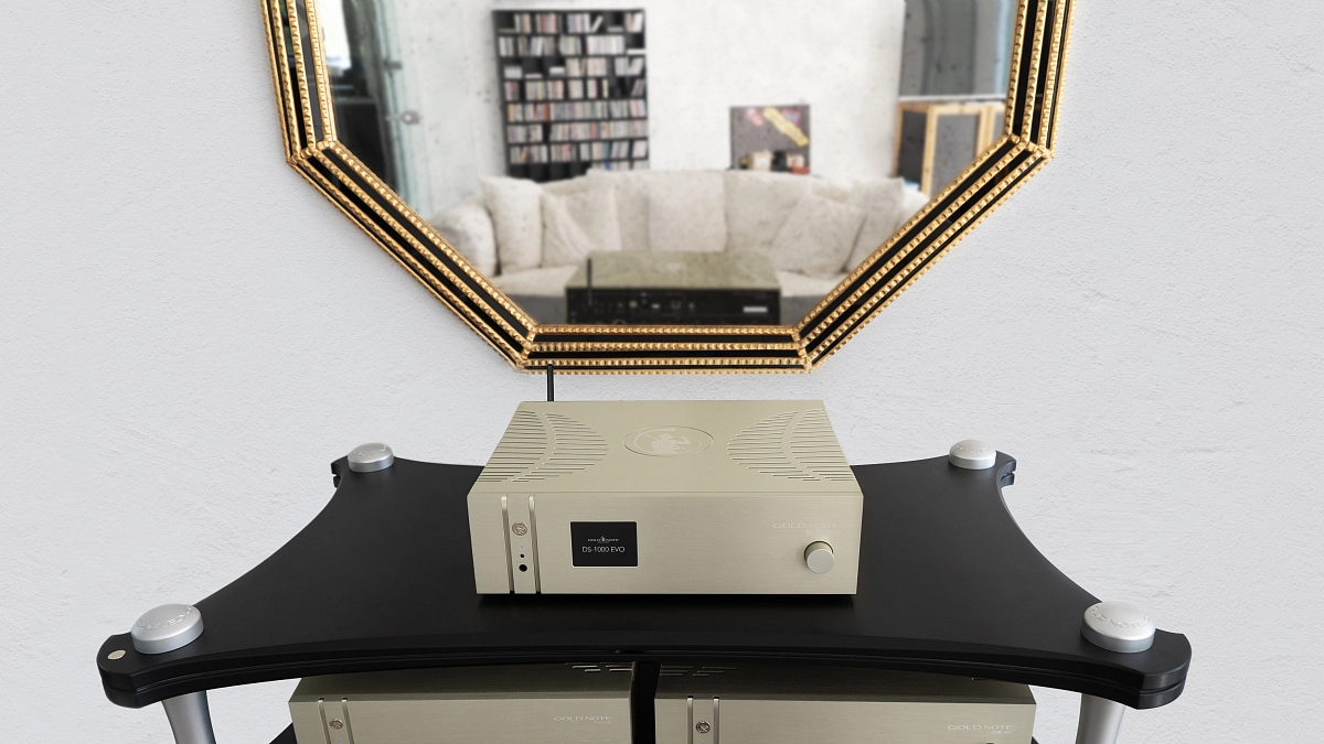 Gold Note DS-1000 EVO na audio racku v obývacím pokoji s policemi na vinyl a zlatým zrcadlem nad ním