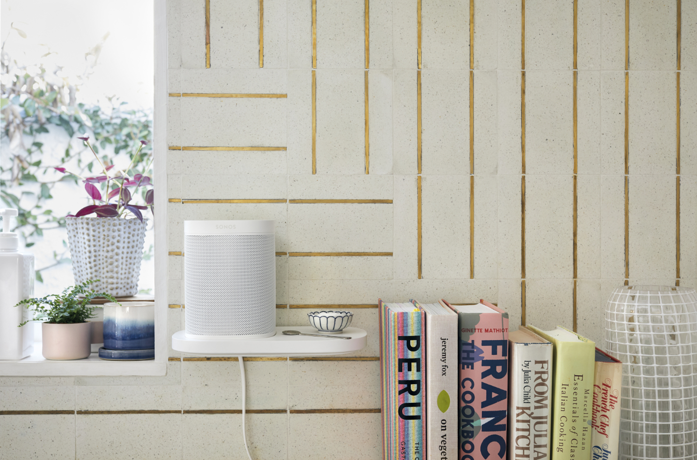 Bílá Sonos Shelf Polička na zdi v kuchyni s bílým reproduktorem Sonos One, knihami a rostlinami