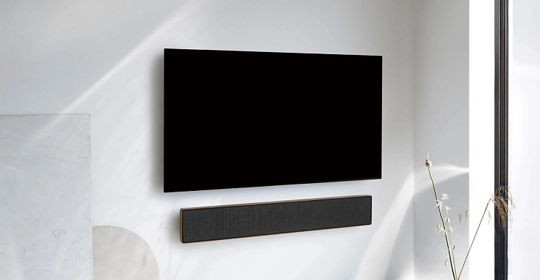 Soundbar Beosound Stage zavěšený na stěně pod televizorem v obývacím pokoji